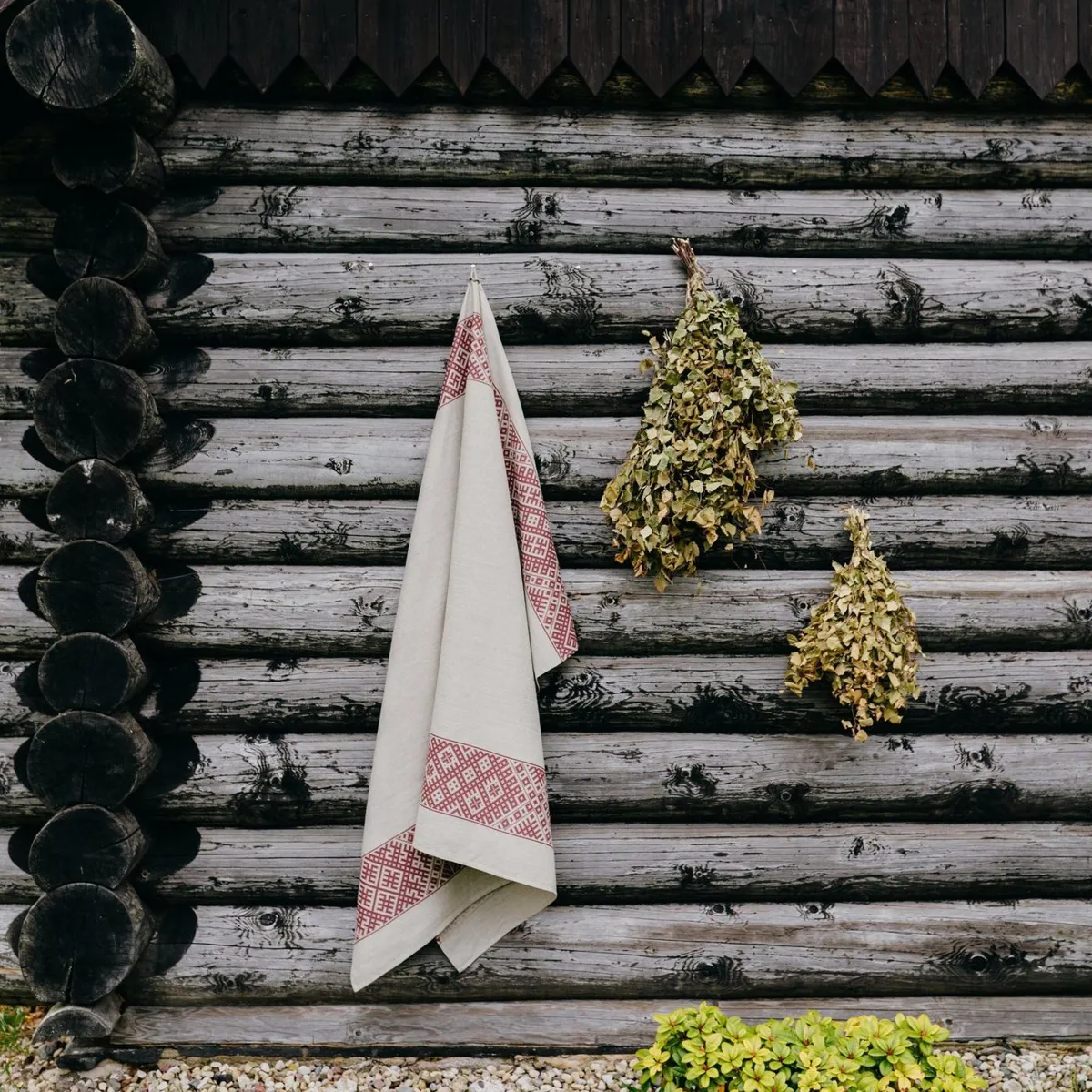 Lina pirts dvielis ar Lielvārdes jostu pie guļbūves sienas